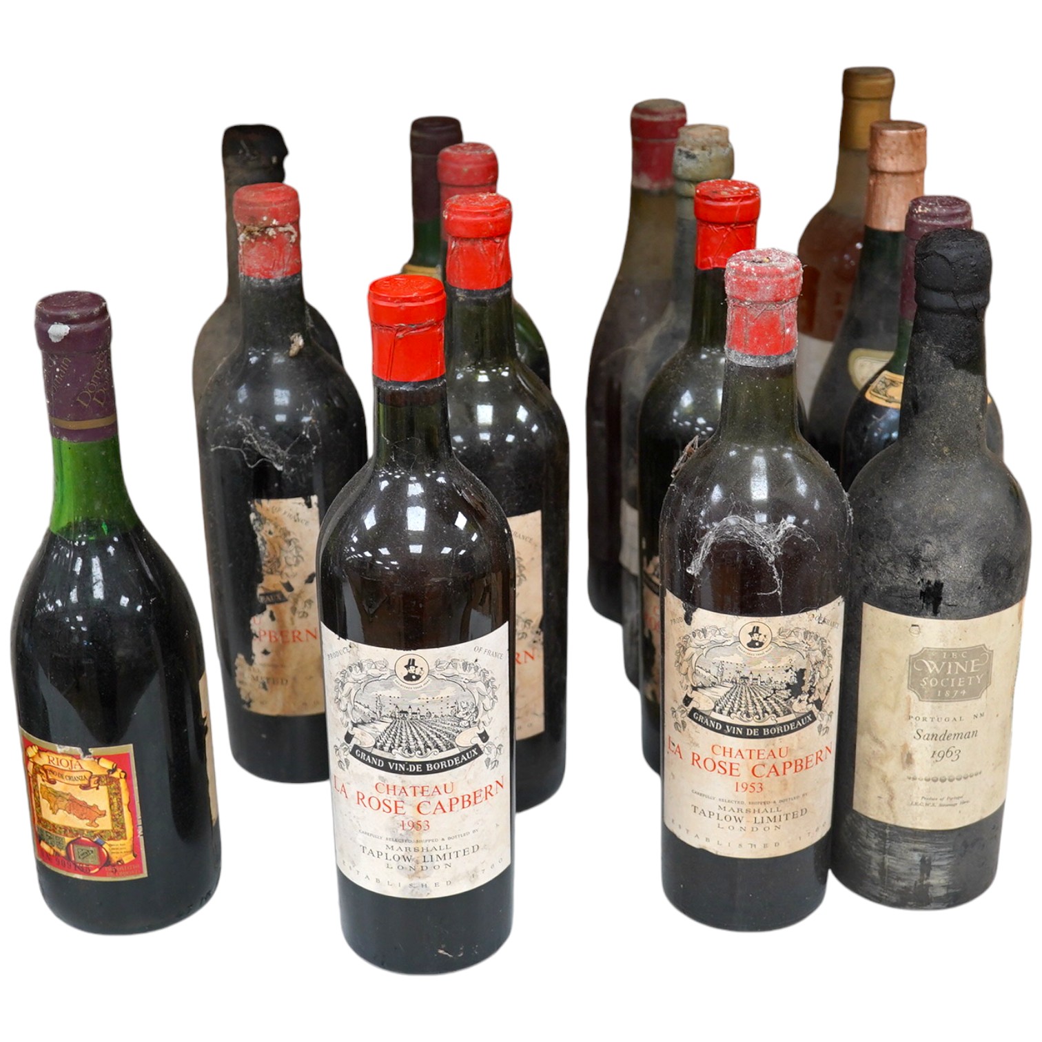 Fifteen bottles of wine and fortified wine, including; a Sandeman 1963 port, four bottles of Chateau La Rose Capbern 1953, a 1976 Madiran Cuvee de la Confrerie, etc. Condition - poor to fair, storage history unknown